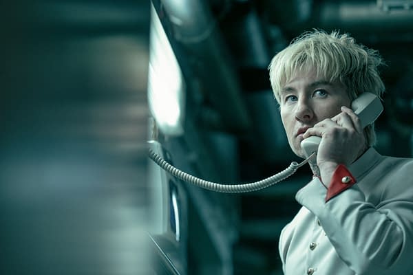 Barry Keoghan stars as Ormon, holding a vintage telephone in an industrial setting, wearing a light-colored uniform with distinct red accents. The atmosphere evokes a sense of tension and mystery.