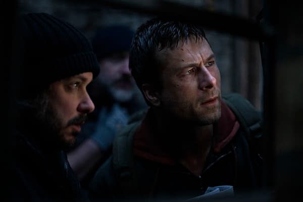 Director Edgar Wright and actor Glen Powell are captured in a tense moment on the set of "The Running Man," exhibiting expressions of focus and intensity.