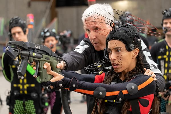 Director James Cameron guides actress Oona Chaplin on the set of 'Avatar: Fire and Ash,' as she uses a motion capture gun and wears a specialized suit, surrounded by crew members in motion capture attire.