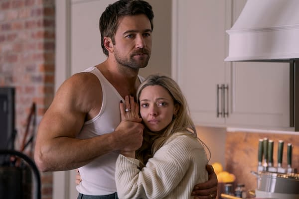 Brandon Sklenar as Andrew Winchester and Amanda Seyfried as Nina Winchester in a dramatic embrace in a kitchen setting. The scene reflects tension with emotional expressions amidst a domestic backdrop.