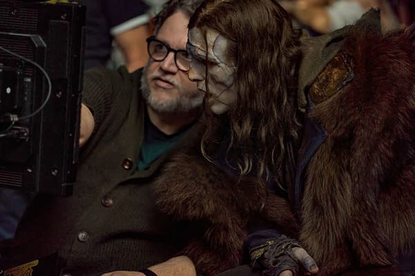 On the set of 'Frankenstein,' writer/director Guillermo del Toro and actor Jacob Elordi, portraying The Creature, are seen together, focused on a monitor. Elordi is dressed in a dark costume with a fur element and has a pale, weathered appearance.