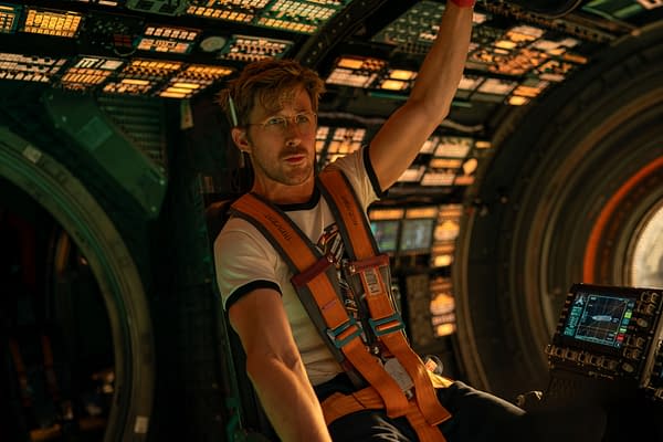 Ryan Gosling as Ryland Grace in a space cockpit, wearing an orange harness over a t-shirt, focuses intently while controlling a futuristic panel filled with screens and buttons from the film Project Hail Mary.