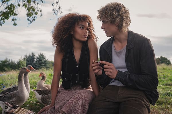 Still from The Hunger Games: Sunrise on the Reaping featuring Whitney Peak as Lenore Dove Baird and Joseph Zada as Haymitch Abernathy, seated together on the grass with geese nearby, conveying a moment of connection.