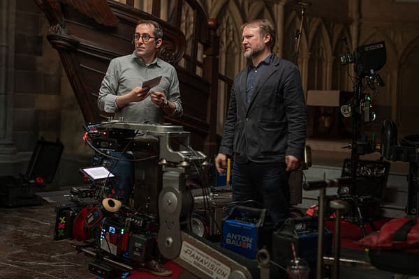 Behind-the-scenes photo from the set of 'Wake Up Dead Man: A Knives Out Mystery', featuring Writer/Director Rian Johnson and Director of Photography Steve Yedlin discussing a scene, with film equipment in the foreground.
