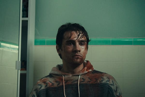 Michael Johnston stars as Bear in the film 'Obsession', with a distressed expression, blood on his face, and wearing a patterned hoodie. The background is a tiled bathroom.