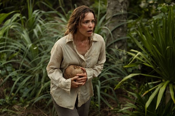 Rachel McAdams portrays Linda Liddle in a tense moment from 20th Century Studios' film 'SEND HELP,' showing her with a distressed expression while holding a coconut, surrounded by dense greenery.