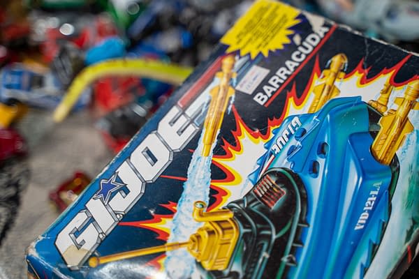 Close-up of a vintage G.I. Joe Barracuda toy packaging featuring vibrant colors and retro graphics, showcasing a toy vehicle among other collectibles at a flea market in Ankara, Turkey.