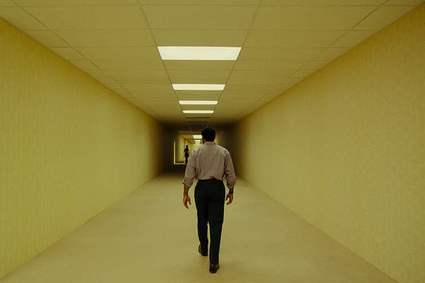 A lone man walks down a long, eerie yellow hallway with fluorescent ceiling lights, evoking the Backrooms. Another figure stands far ahead in the distance.