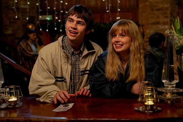 Spike Fearn and Angourie Rice sit side by side at a warmly lit bar in Finding Emily, smiling as they look off-camera.