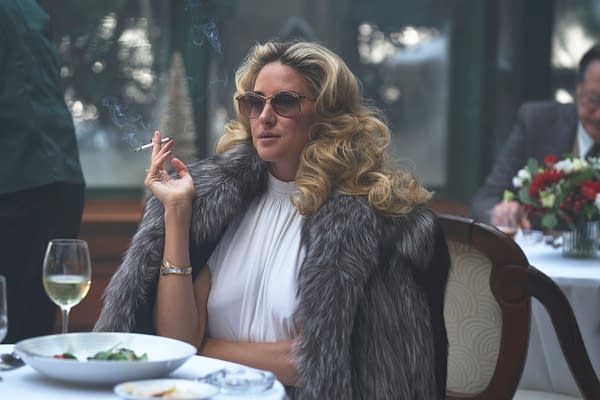Blonde woman in sunglasses and a fur stole smokes a cigarette at a restaurant table in Motor City.