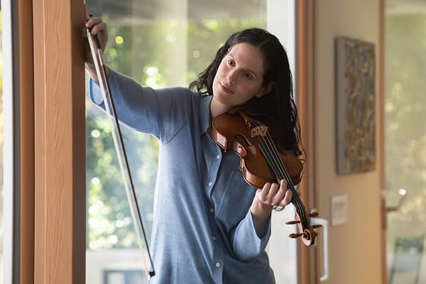 Eva Victor holds a violin and bow in a sunlit room in BEHEMOTH!