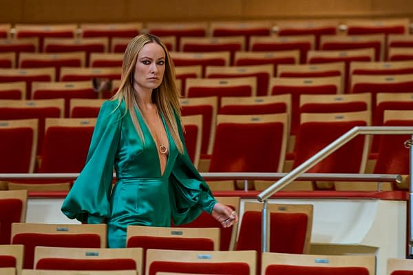 Olivia Wilde stands in an empty theater wearing a teal dress in a still from BEHEMOTH!.