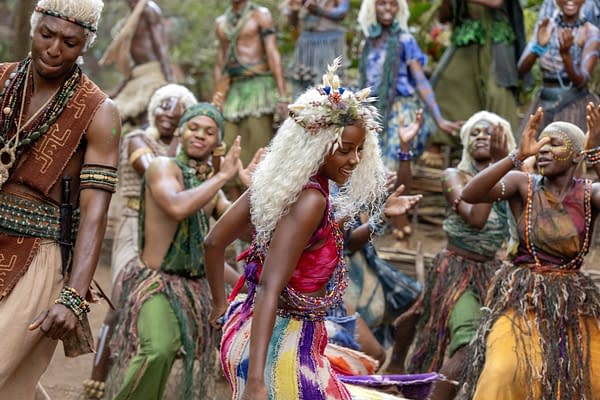 Thuso Mbedu as Zélie dances in a colorful ceremonial scene from Children of Blood and Bone, surrounded by other performers in tribal-inspired costumes.