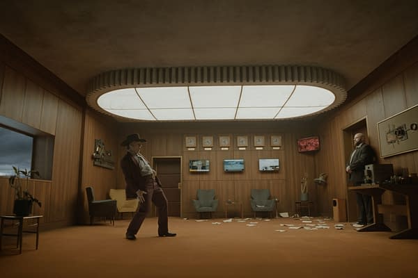 A cinematic western-style office interior with a man in a cowboy hat standing in the center and another man by the wall, under a large ceiling light. Papers are scattered across the floor, and monitors and clocks line the back wall.