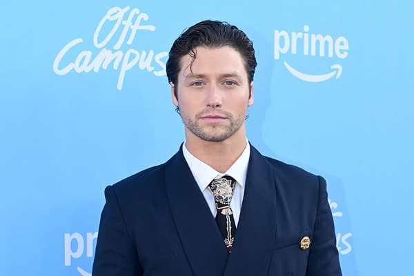 Stephen Kalyn poses on a blue Off Campus and Prime event backdrop in a dark suit and patterned tie.