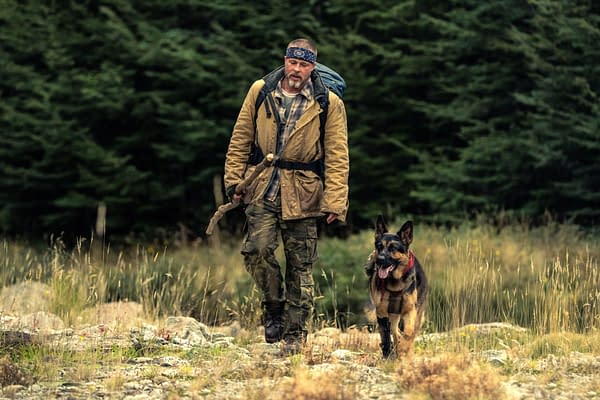 Brad Pitt as James Belmont walks through a grassy forest clearing with a German shepherd in Heart of the Beast.