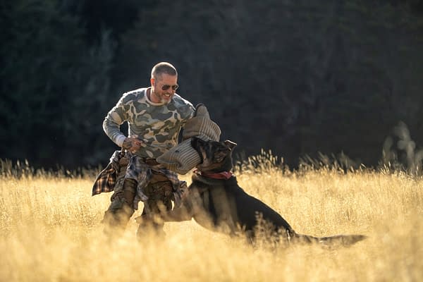 Brad Pitt as James Belmont stands in a sunlit field, training with a German shepherd in Heart of the Beast.