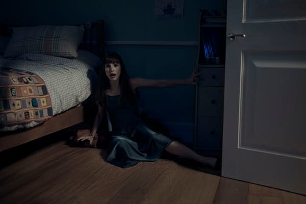 Jessica Chastain sits on the floor of a dark child's bedroom in a tense scene from Other Mommy, reaching toward the open door.