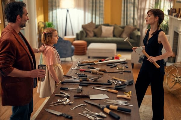 Daddo, Bela, and Mommy stand in a living room beside a table covered with knives and tools in a scene from Other Mommy.