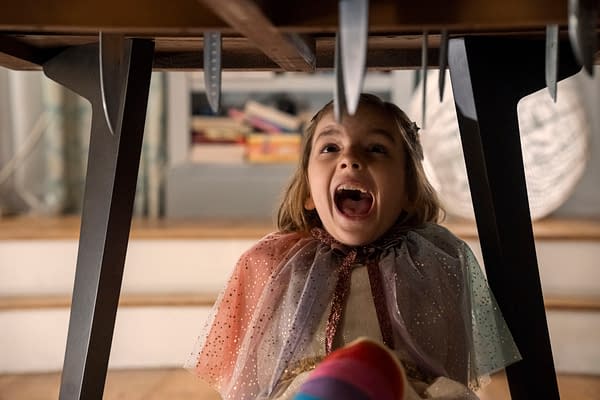 Arabella Olivia Clark as Bela in Other Mommy screams under a table with hanging blades above her.