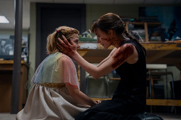 Bela and Mommy sit face-to-face in a tense moment, with Mommy's hands on Bela's cheeks and blood smeared on her arm and face in Other Mommy.