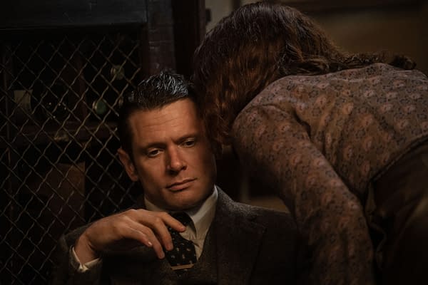 Jack O'Connell as Lamb in Ink, seated in a dimly lit scene while a woman leans over him in the foreground.