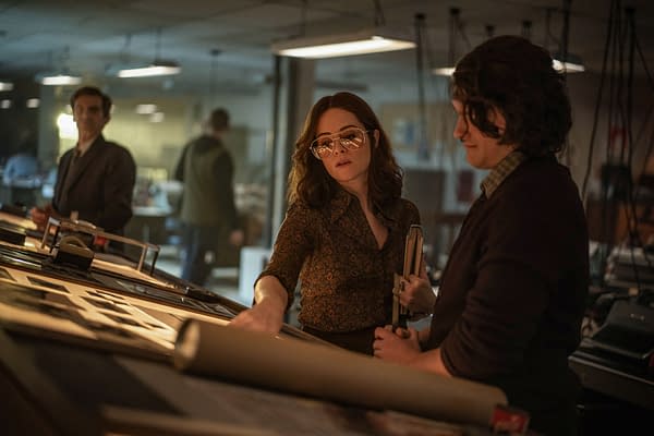 Claire Foy as Jules Davies in Ink, standing in a dimly lit office and studying papers with a colleague.
