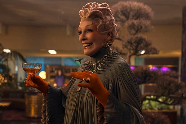 Glenn Close as Drusilla Sickle in The Hunger Games: Sunrise on the Reaping, holding a gold goblet and smiling in an ornate, futuristic setting.