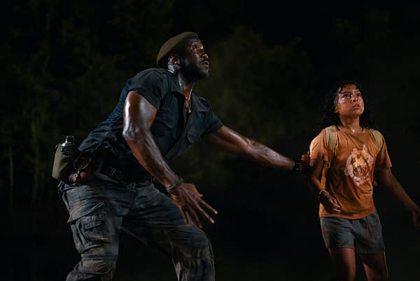 A scene from 'Jurassic World Rebirth' featuring Mahershala Ali as Duncan Kincaid and Audrina Miranda as Isabella Delgado, both in a tense moment, with Kincaid reaching out protectively towards Delgado, who appears anxious.