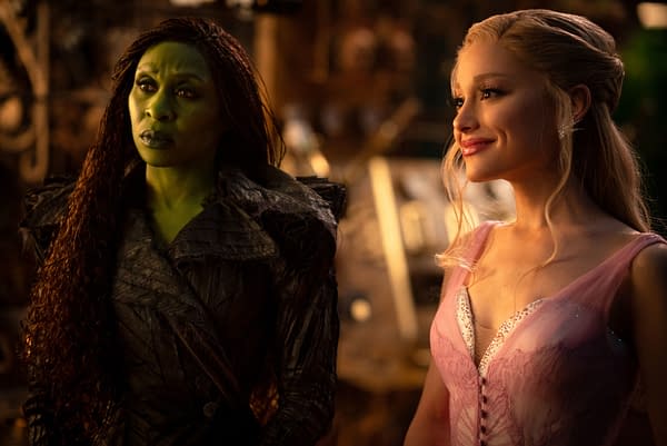 Cynthia Erivo as Elphaba, with green skin and a dark, textured outfit, stands next to Ariana Grande as Glinda, who wears a light pink gown and smiles warmly. This scene is from 'WICKED FOR GOOD,' directed by Jon M. Chu.