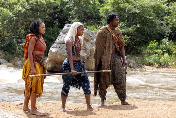 Amandla Stenberg, Thuso Mbedu, and Tosin Cole stand in costume by a river in Children of Blood and Bone, looking ready for a journey.