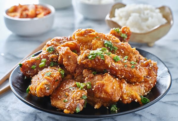 Crispy fried korean chicken wings in galbi sauce with pickled radish, kimchi, and rice side dishes, photo by Joshua Resnick/Shutterstock.com.