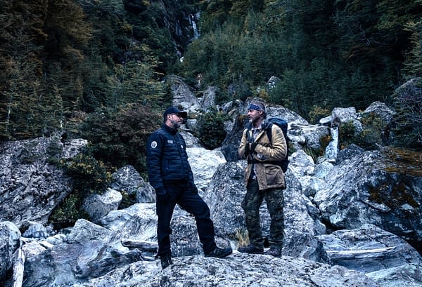 Director David Ayer and Brad Pitt stand on rocky terrain in a forested mountain setting on the set of Heart of the Beast.