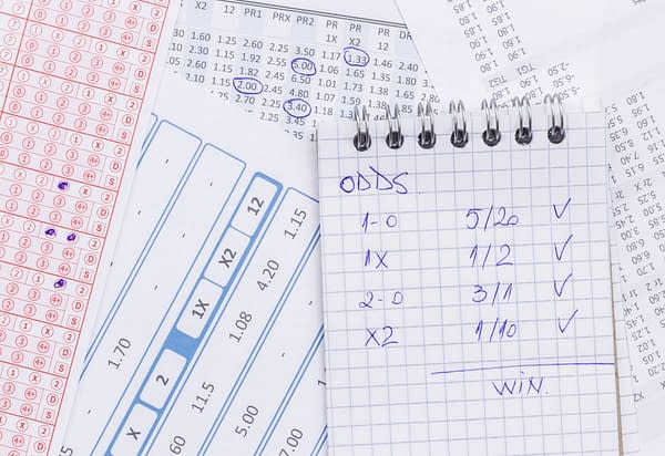 Notebooks and reciepts with betting odds, image by ggserban/Shutterstock.com.