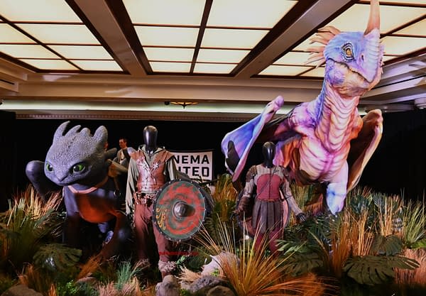 A display featuring large, colorful figures of dragons and characters from a fantasy series. The scene showcases a dragon with bright scales alongside a character in medieval-style armor, against a backdrop of lush vegetation.