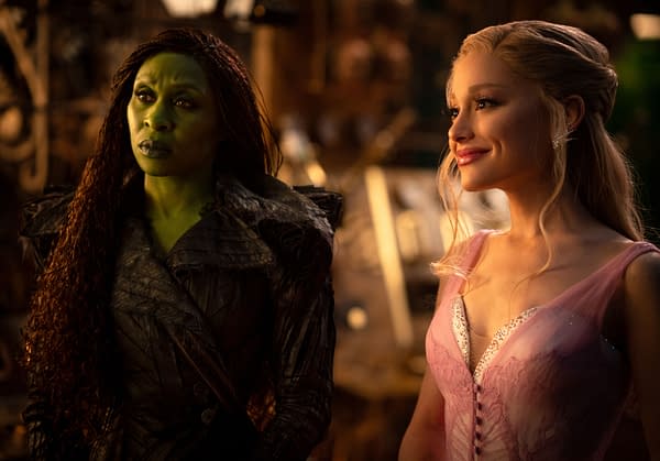 Cynthia Erivo as Elphaba, with green skin and a dark, textured outfit, stands next to Ariana Grande as Glinda, who wears a light pink gown and smiles warmly. This scene is from 'WICKED FOR GOOD,' directed by Jon M. Chu.