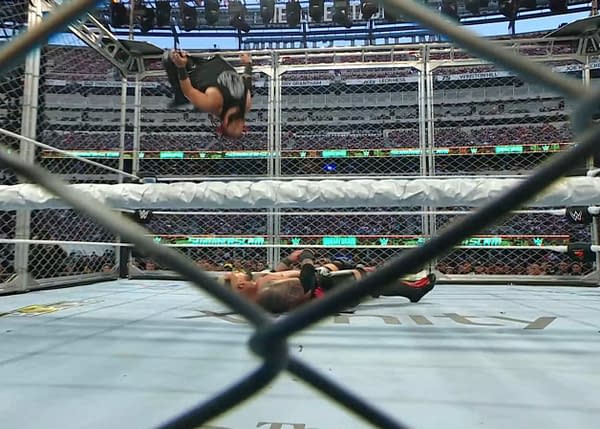 Jacob Fatu performs a moonsault off a steel cage during a wrestling match, with Solo Sikoa on the mat below and a steel cage surrounding the ring.
