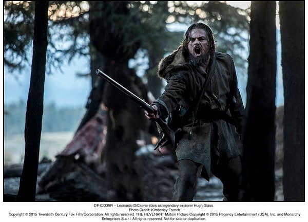 A scene from the film 'The Revenant' featuring Leonardo DiCaprio as Hugh Glass, shouting fiercely while holding a firearm in a forested area.