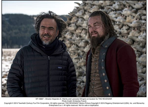 Director Alejandro G. Iñárritu and actor Leonardo DiCaprio stand together on location for the film THE REVENANT, with a backdrop of animal bones in a snowy landscape.