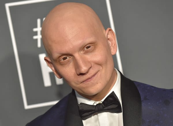Anthony Carrigan, a bald actor, smiles while wearing a tuxedo with a bow tie at a red carpet event, showcasing an elegant atmosphere.