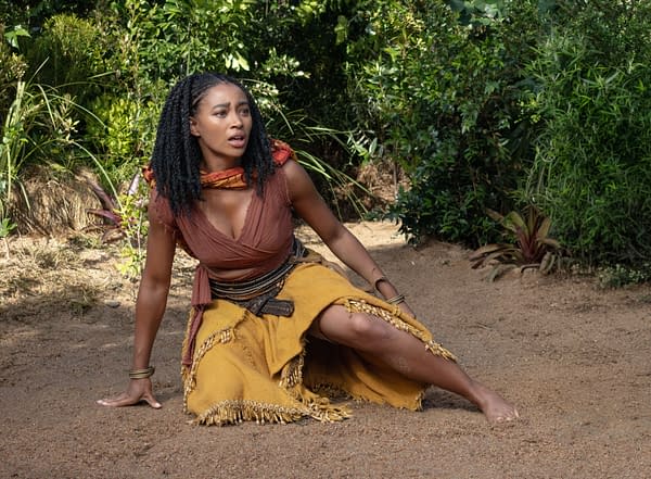 Amandla Stenberg as Amari crouches on a sandy path in a lush jungle setting, looking startled in Children of Blood and Bone.