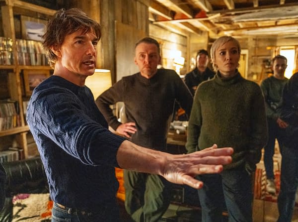 On the set of 'Mission: Impossible - The Final Reckoning,' Tom Cruise gestures while discussing a scene, flanked by Simon Pegg and Pom Klementieff, all dressed in cozy sweaters.