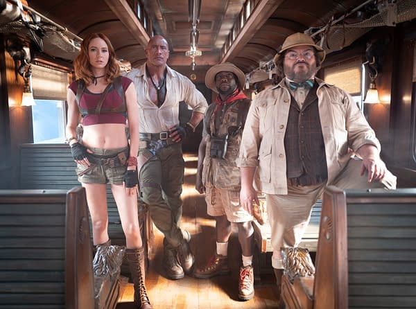 Four adventurers stand inside a vintage train car, dressed in safari gear and ready for action in Jumanji: Open World.