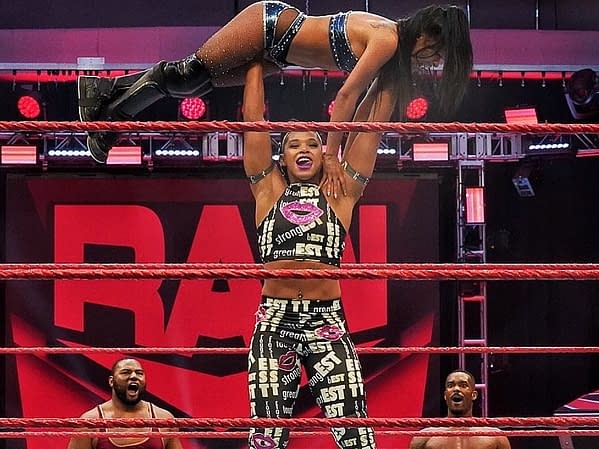 As The Street Profits look on, Bianca Belair presses Zelina Vega over her head on Raw, courtesy of WWE.