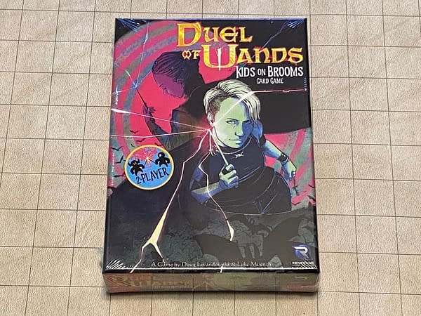 The front cover of the box for Duel of Wands, a card game based in the world of the Kids on Brooms RPG, both games developed by Renegade Game Studios.