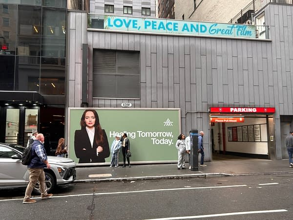 A large billboard displays a woman in business attire, with the text 'Heading Tomorrow, Today' against a green background. Above it, a sign reads 'LOVE, PEACE AND Great Film' on the building.