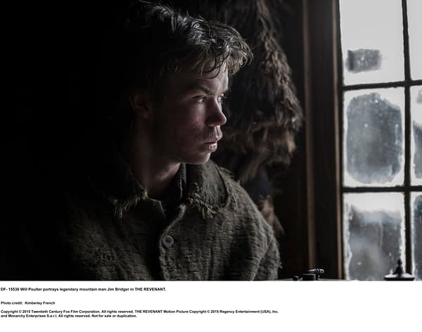 Will Poulter as Jim Bridger, a legendary mountain man, gazes pensively out of a window in a rustic setting from the film THE REVENANT.