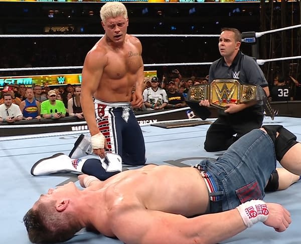 Cody Rhodes stands beside a defeated John Cena in the ring at WWE SummerSlam, with a referee holding the WWE Championship belt.