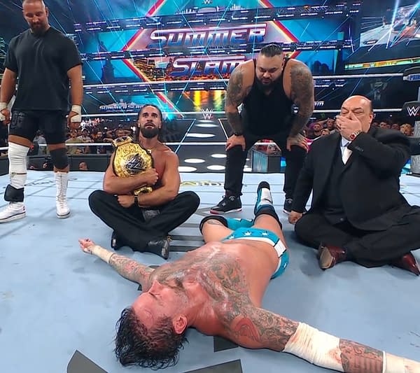 At WWE SummerSlam, Seth Rollins sits in the ring holding a championship belt while a defeated CM Punk lies on the mat. Rollins' allies survey the wreckage.