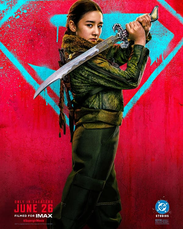 Supergirl movie poster showing a young woman in a green outfit holding a sword against a bright pink and blue graffiti-style background.